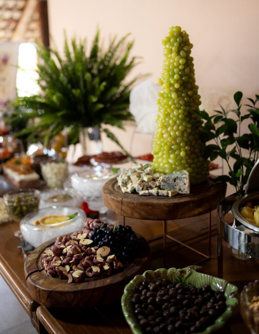 Mesa de buffet com queijos, frutas, doces e decoração verde
